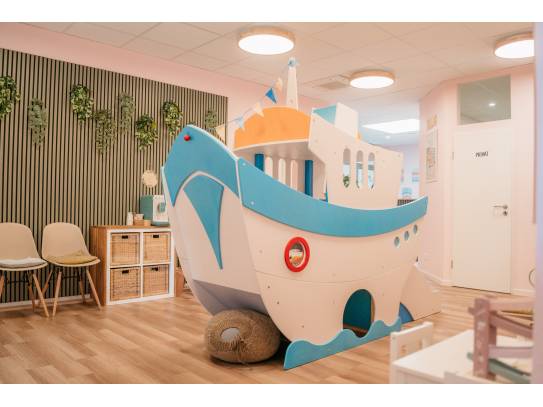 Innenraum mit fantasievollem Holzspielschiff, Stühlen und gemütlicher Atmosphäre