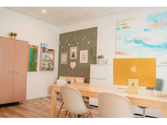 Innenraum mit Tisch, Stühlen, Kinderecke, farbigen Möbeln und kreativer Wandgestaltung