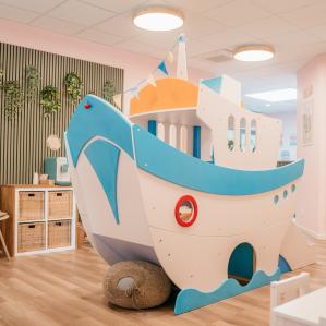 Innenraum mit großem Holzspielschiff, Sitzgelegenheiten und dekorativer Wandgestaltung