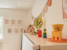 Detailaufnahme eines Spielzeugregals mit Holzspielzeug und bunter Wanddekoration